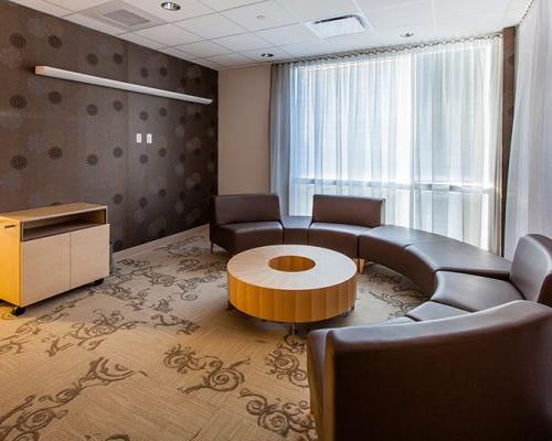 图为加州质子癌治疗中心的座位. 圆形棕色皮革沙发围绕着甜甜圈形状的桌子.
